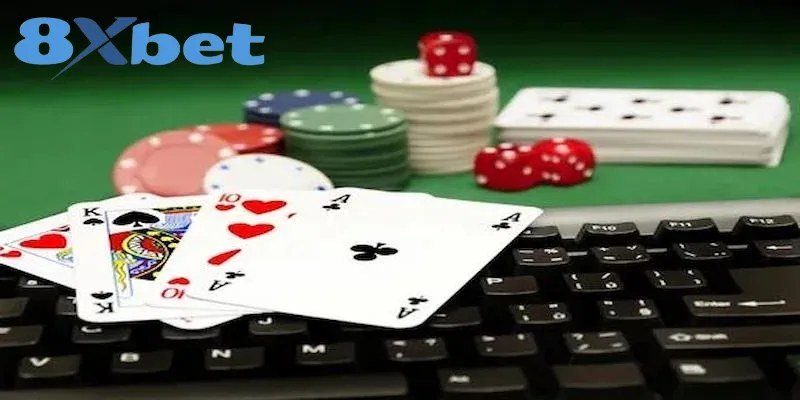 Lá bài, xúc xắc và chip đặt cạnh bàn phím khi chơi poker online